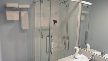 Un baño moderno con ducha de vidrio, inodoro y lavamanos con espejo.