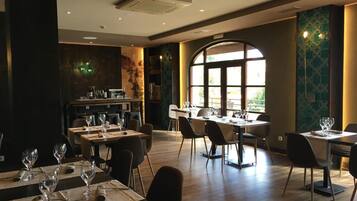 Un restaurante con varias mesas, sillas y un amplio ventanal que permite la entrada de luz natural.