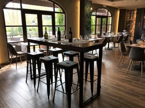 Un restaurant doté d’un bar central, de tables hautes et de tabourets de bar.