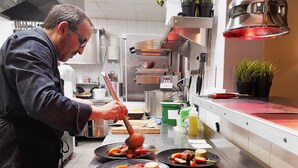 Um chef preparando comida em uma cozinha moderna com eletrodomésticos de aço inoxidável e um layout limpo e organizado.