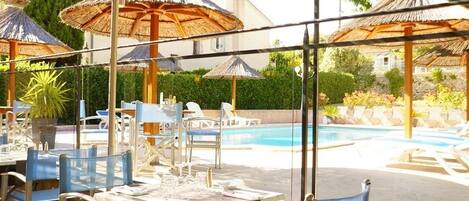 An outdoor pool area with lounge chairs, umbrellas, and tables.