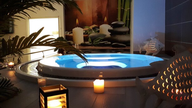 Uma área de spa com hidromassagem, velas e pedras decorativas.