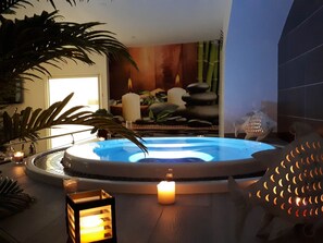 Un espace de bien-être comprenant un bain à remous, des bougies et des pierres décoratives.