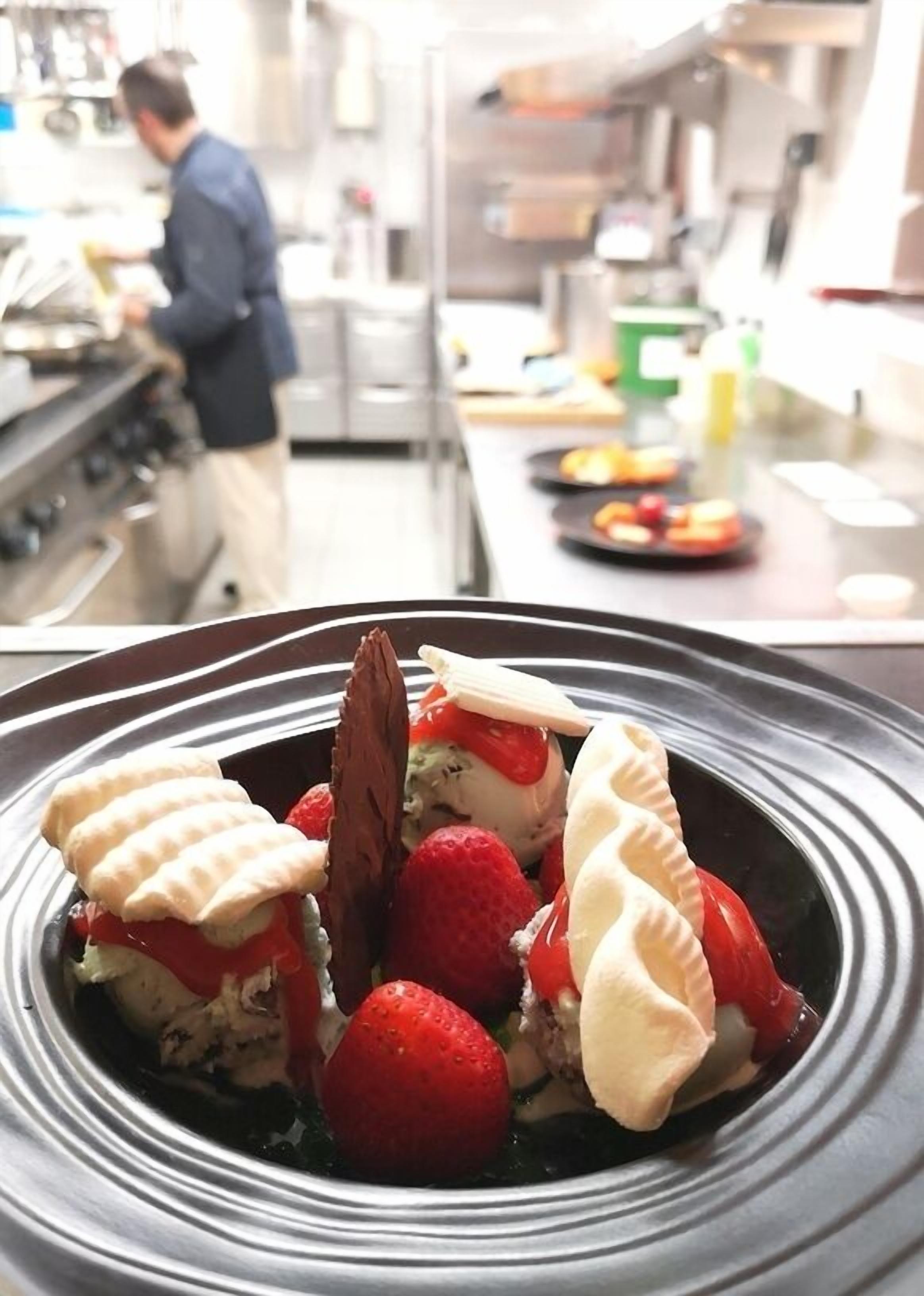 A dessert plate with strawberries and chocolate on a black and white striped plate.