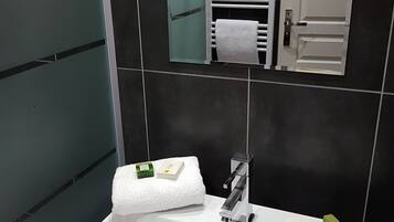 Un baño moderno con un lavamanos blanco, un espejo y un perchero para toallas.