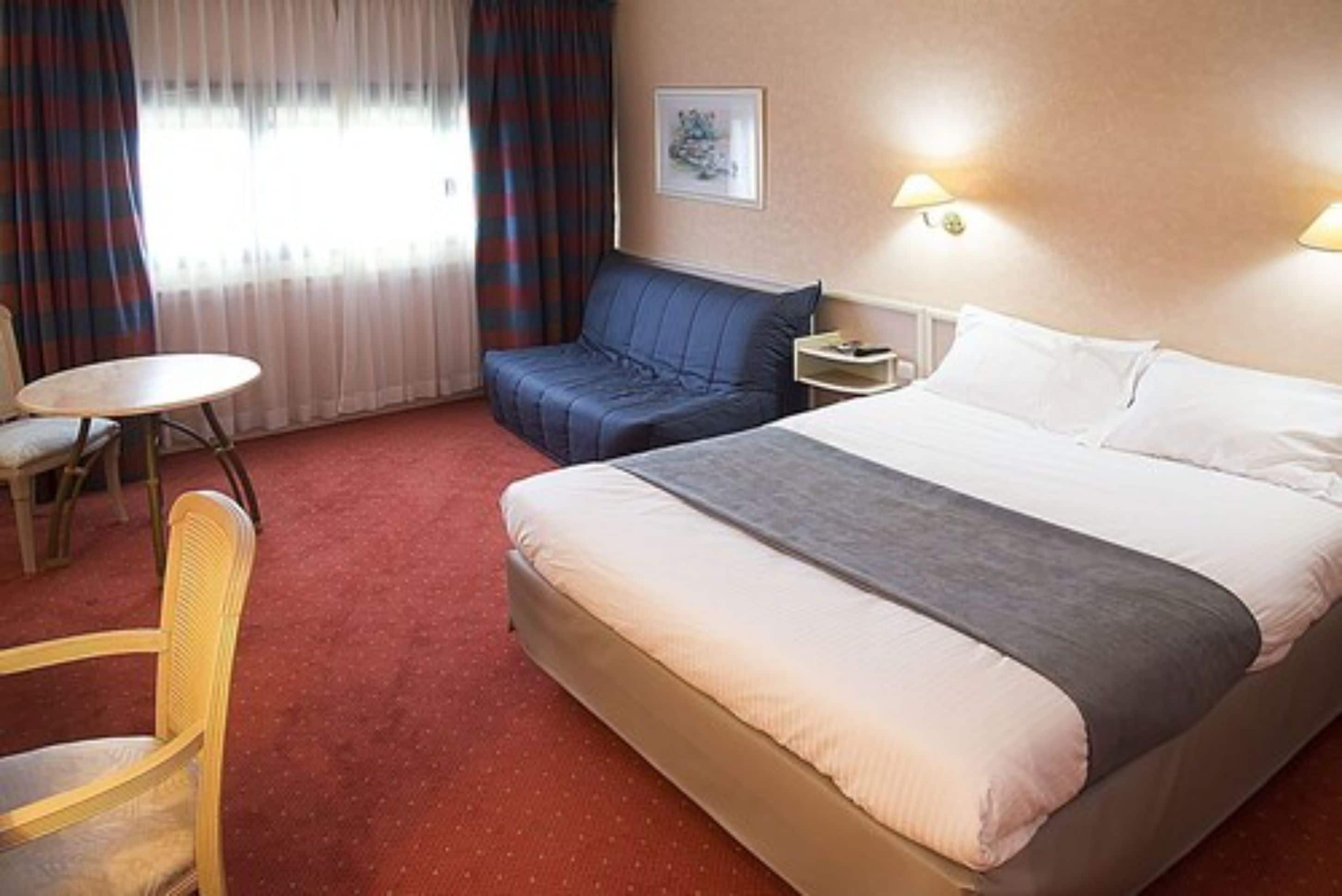 Une chambre d’hôtel avec un lit, un canapé, une petite table et une chaise.