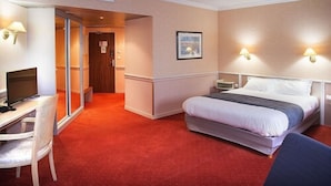 A hotel room with a bed, a desk with a computer, a chair, and two wall-mounted lamps. - Logis Lyon Est (Saint-Maurice-de-Beynost)