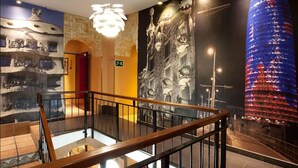 Un hall d’hôtel doté d’un escalier moderne, d’une fresque représentant un bâtiment historique et d’une tour illuminée de façon éclatante.