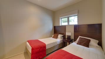 A hotel room with two beds, each with a red blanket and a wooden headboard.