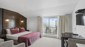 Une chambre d’hôtel avec un lit, un bureau, une chaise et un téléviseur.