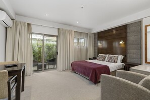 A modern hotel room with a large bed, a desk, and a seating area. - Boulcott Lodge (Lower Hutt)