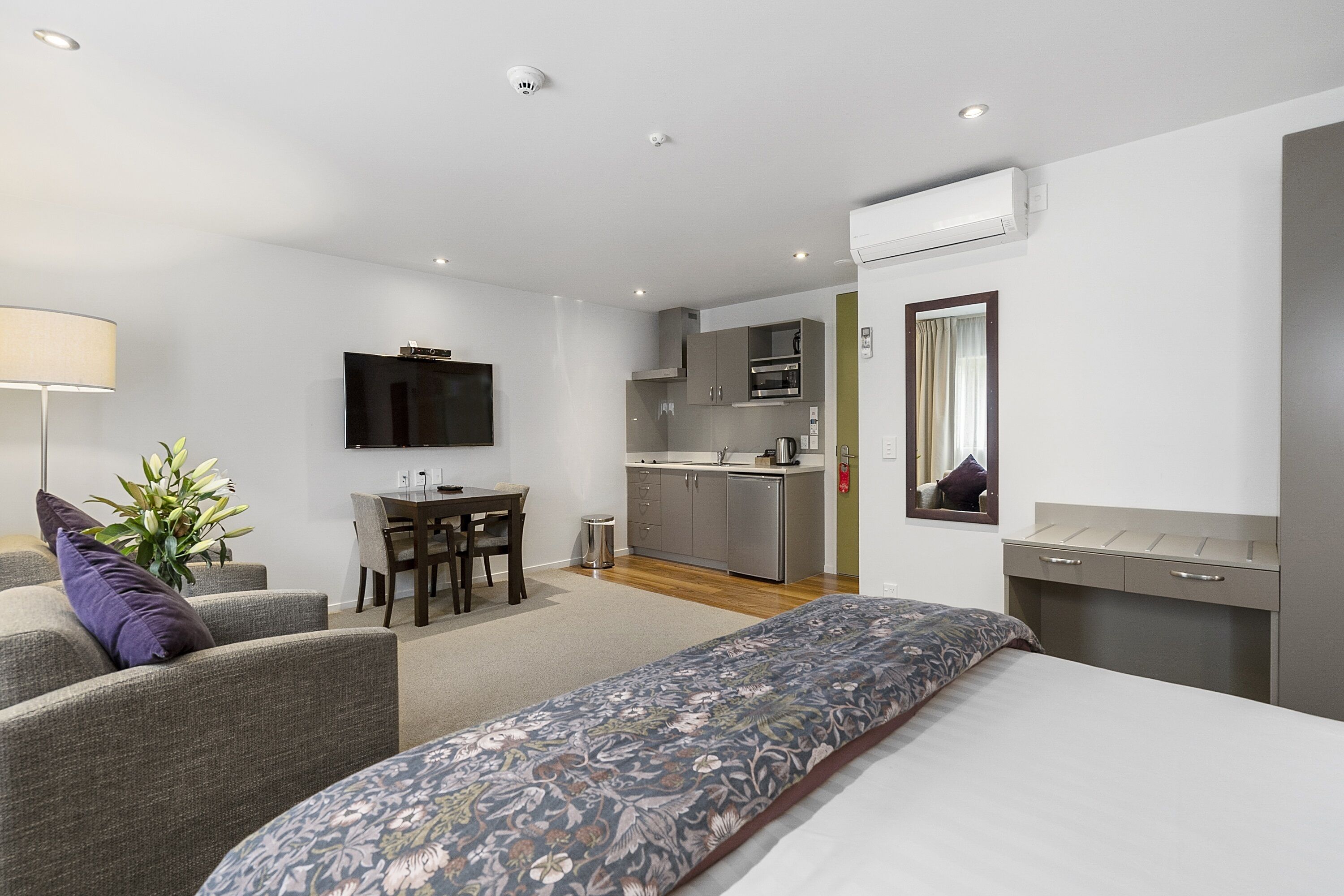 Una habitación de hotel moderna con cama, sofá, escritorio y kitchenette.