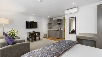 Una habitación de hotel moderna con cama, sofá, escritorio y kitchenette.