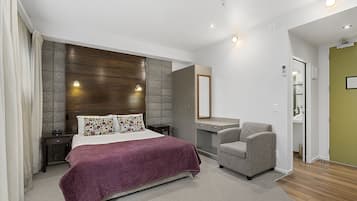 Un dormitorio moderno con una cama grande, una silla, un tocador y un espejo.