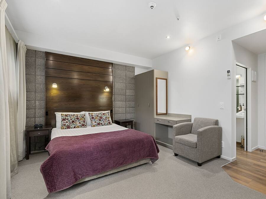 Un dormitorio moderno con una cama grande, una silla, un tocador y un espejo.