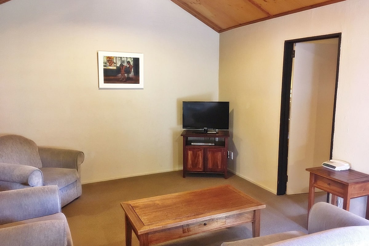 A living room with a television on a wooden stand, a coffee table, and two sofas.