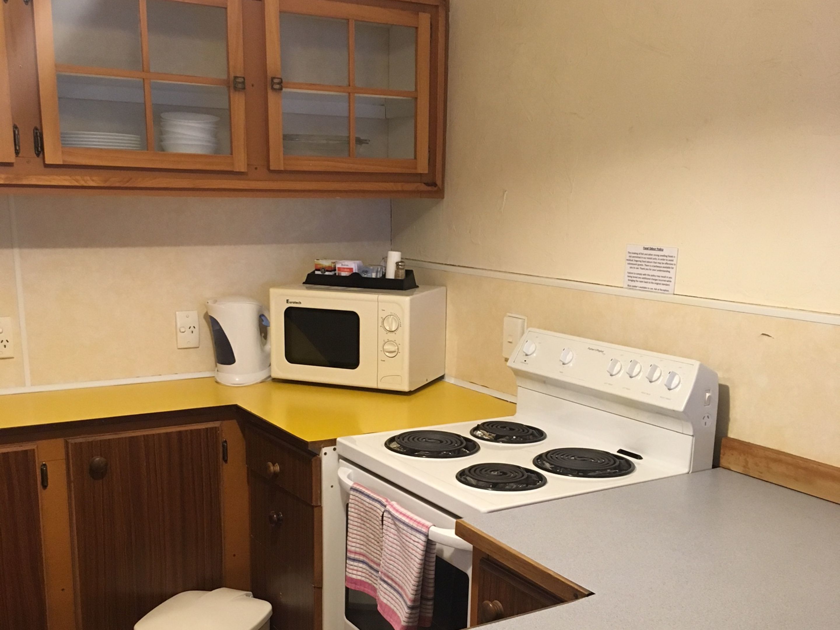 A compact kitchen with a microwave, stove, and wooden cabinets.