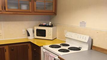 A compact kitchen with a microwave, stove, and wooden cabinets.