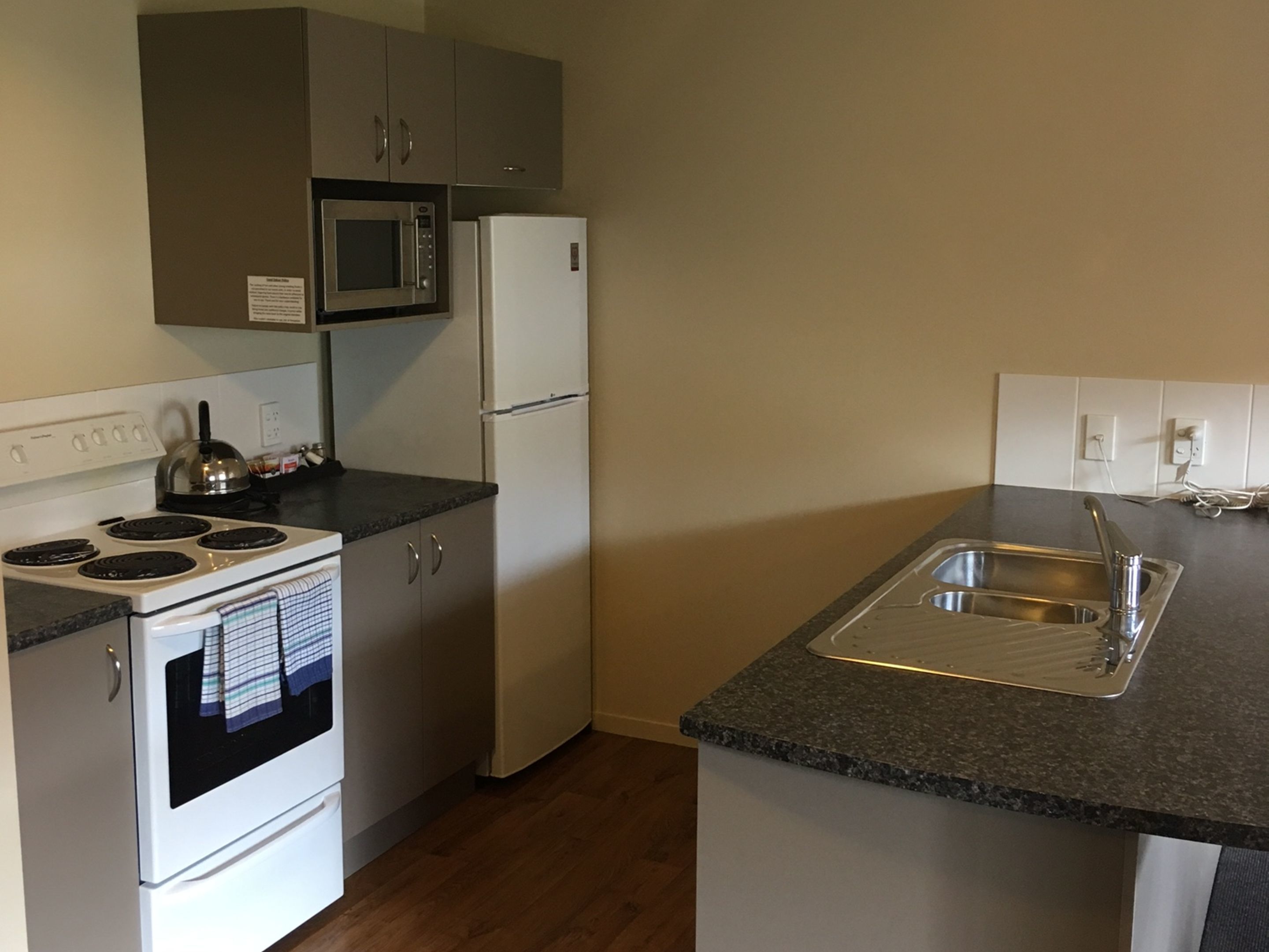Cocina compacta con estufa, microondas, refrigerador y pileta.