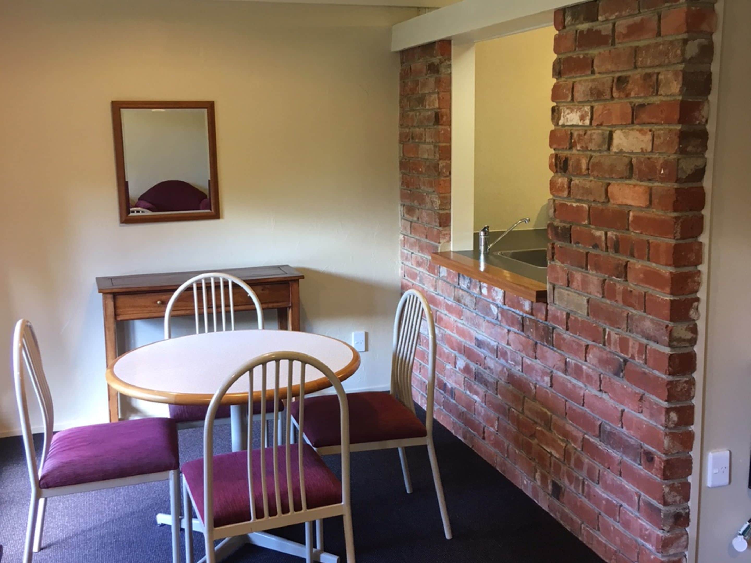 Un coin repas avec un mur en briques, un évier et un miroir.