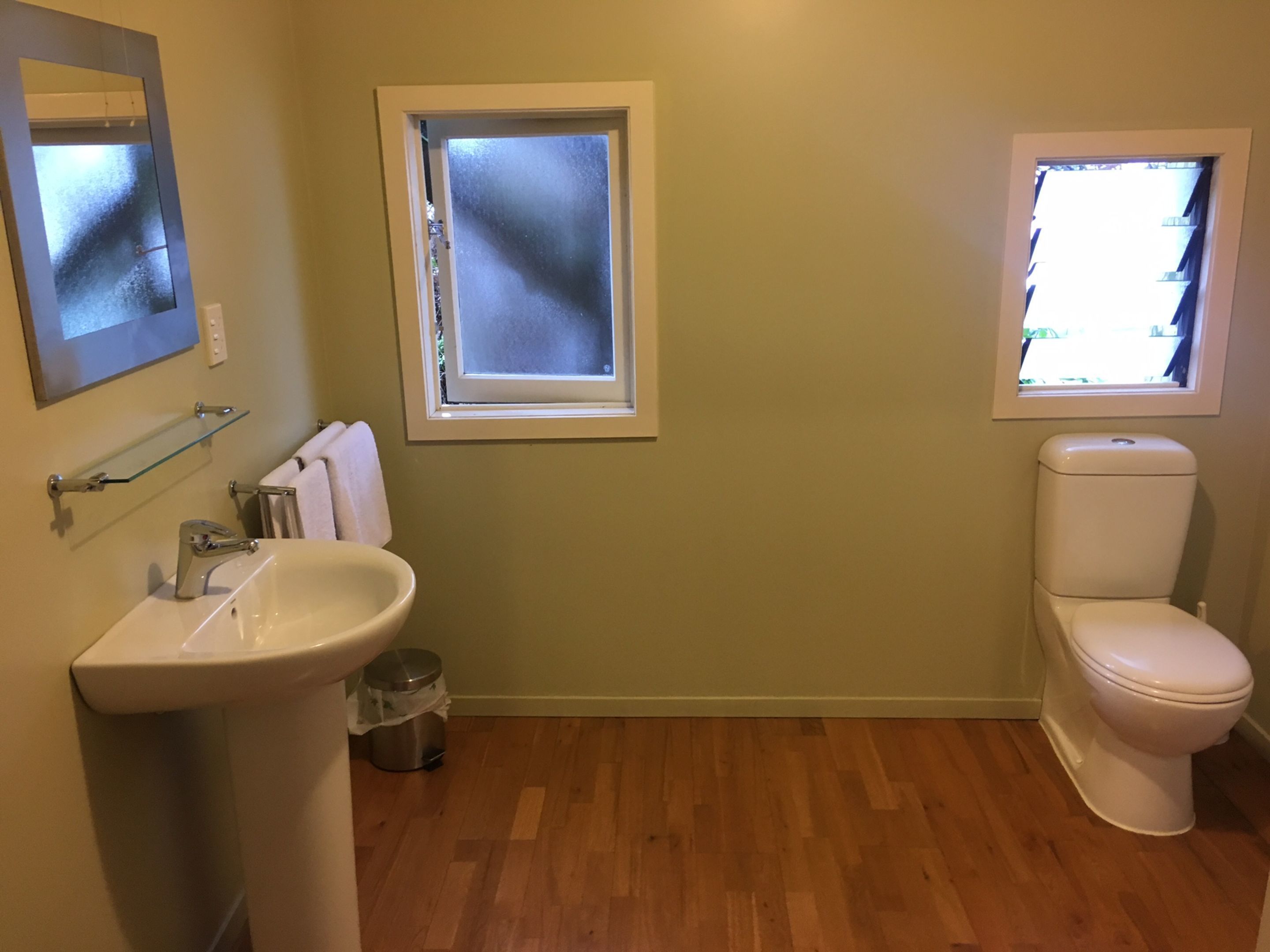 A bathroom with a sink, toilet, and a window.
