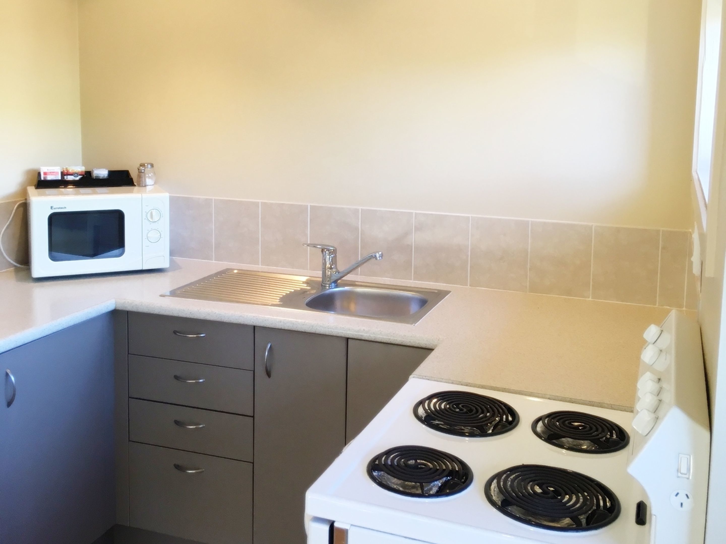 A small kitchen with a microwave, sink, stove, and cabinets.