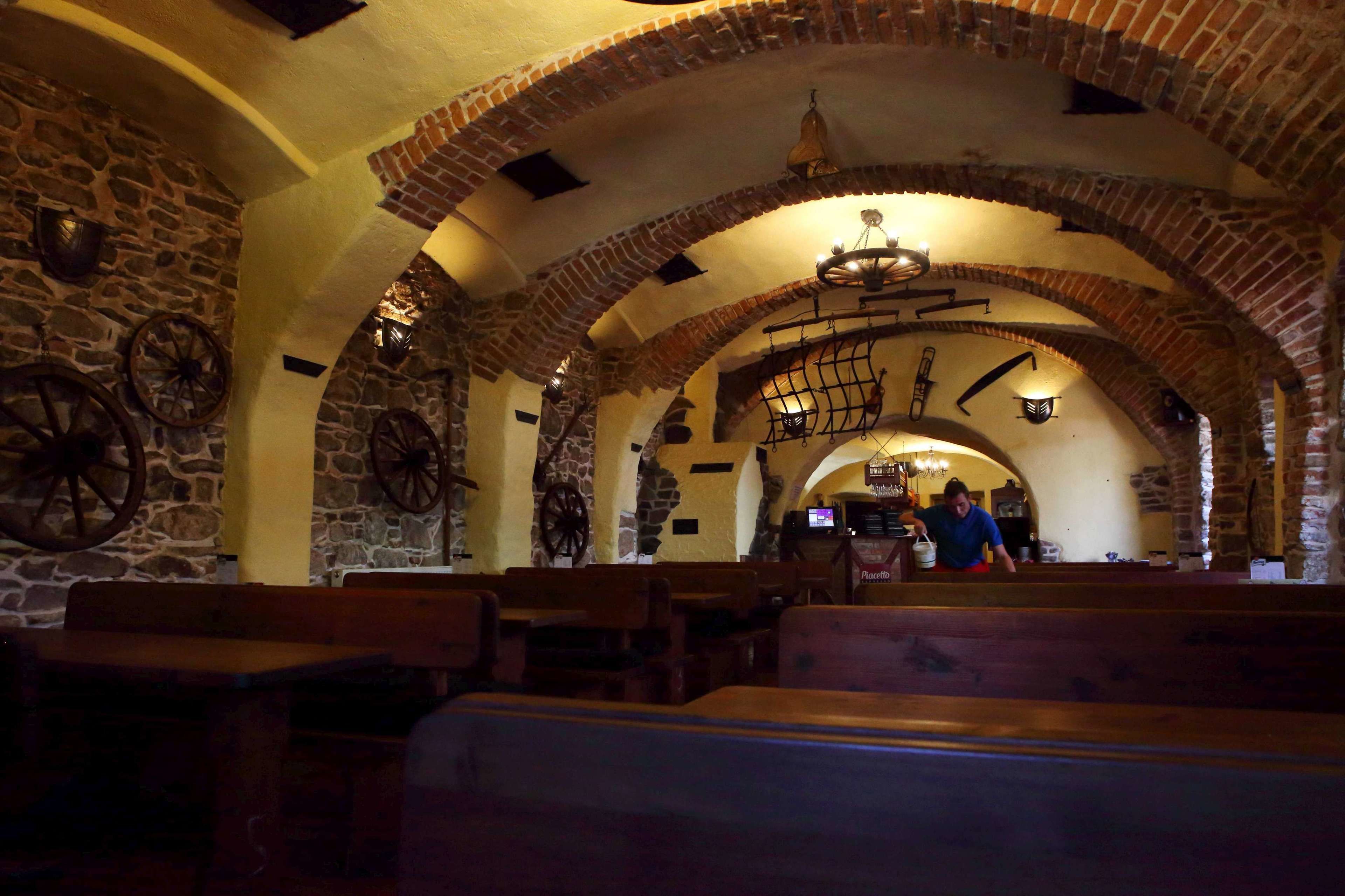 Un interior con paredes de piedra, bancos de madera y arcos de ladrillo.