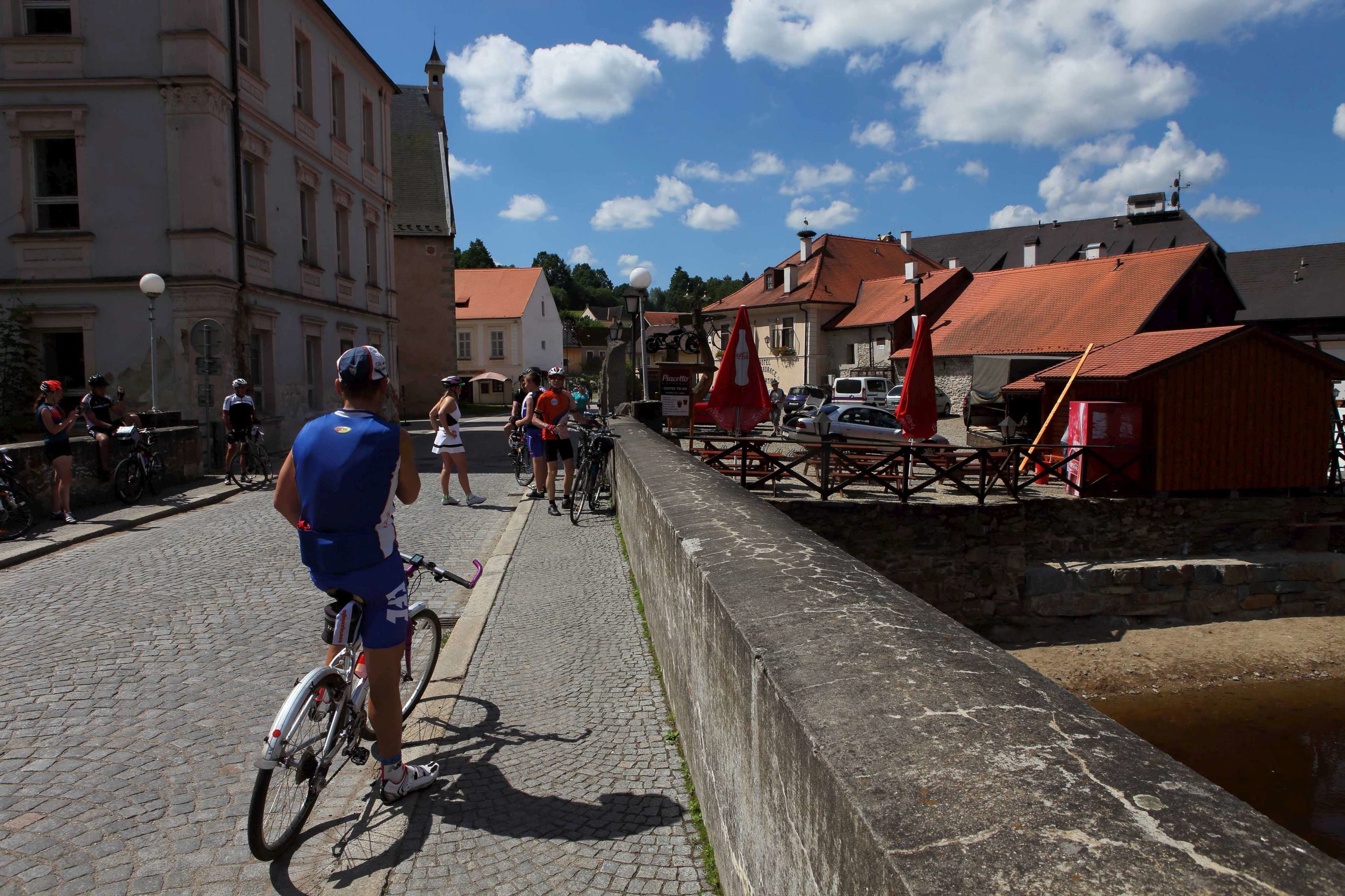 A cobblestone street with cyclists and pedestrians, historic buildings, and a canal.