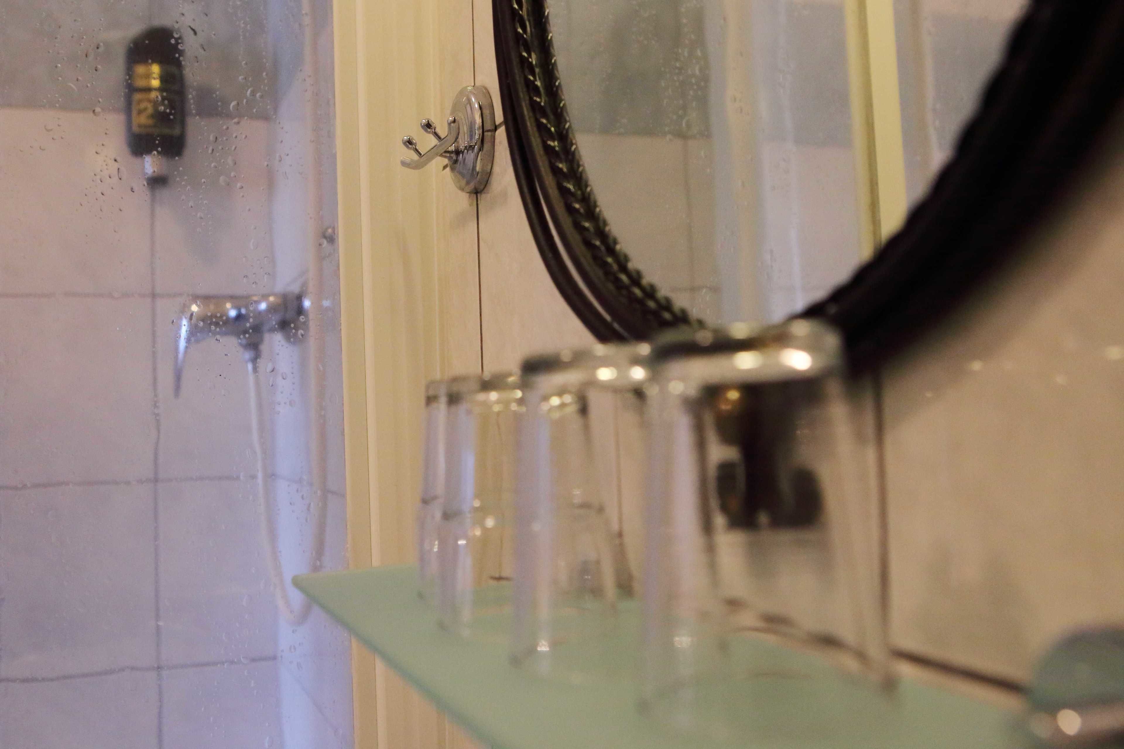 Un baño con cabina de ducha de vidrio, un espejo y un perchero para toallas.