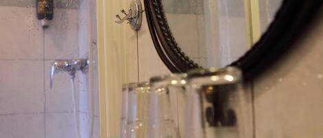 Un baño con cabina de ducha de vidrio, un espejo y un perchero para toallas.