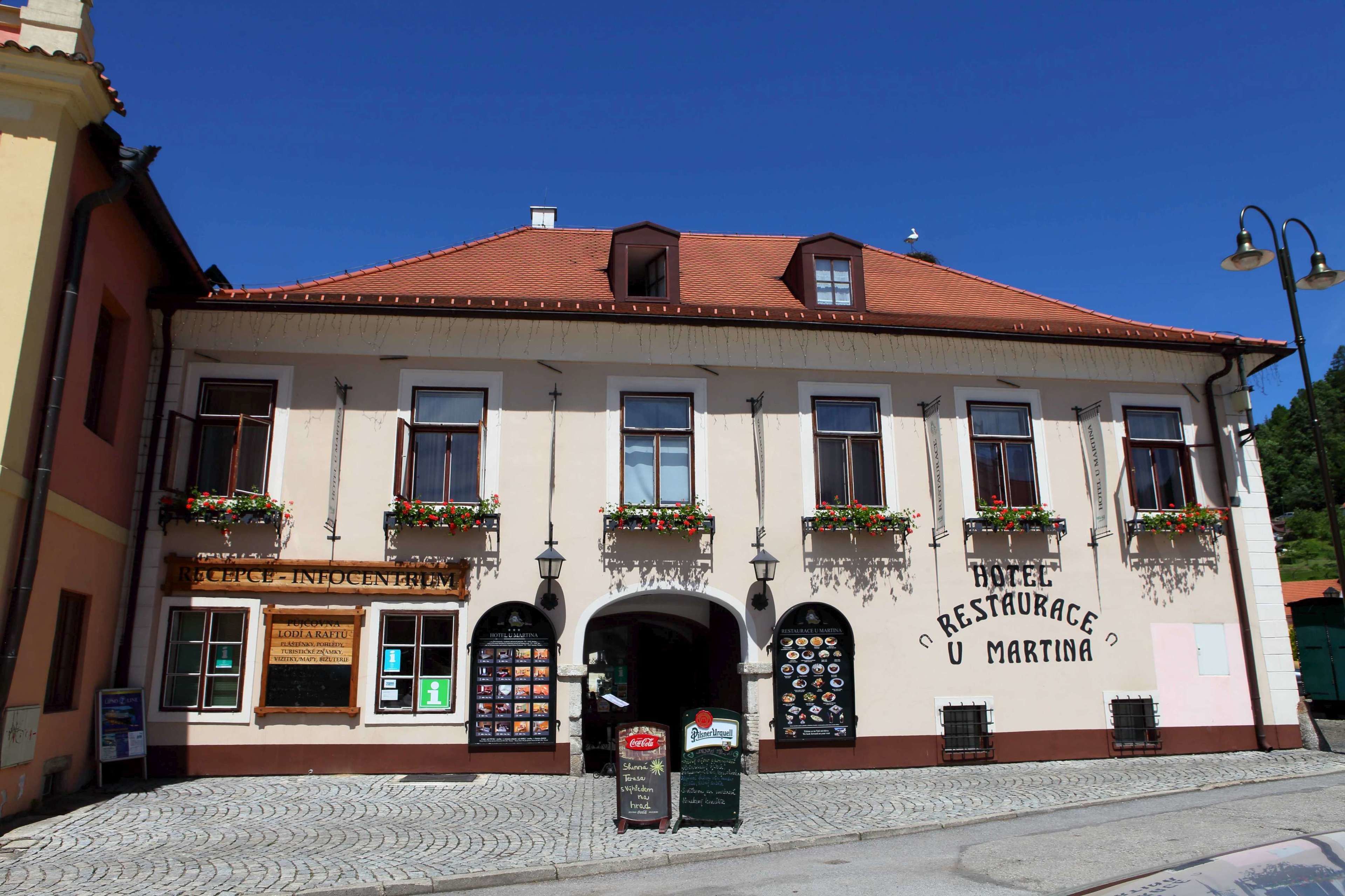 A building with a sign for a hotel and restaurant, multiple windows, and flower boxes on the facade.