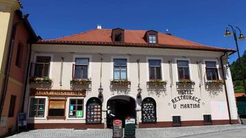 A building with a sign for a hotel and restaurant, multiple windows, and flower boxes on the facade.