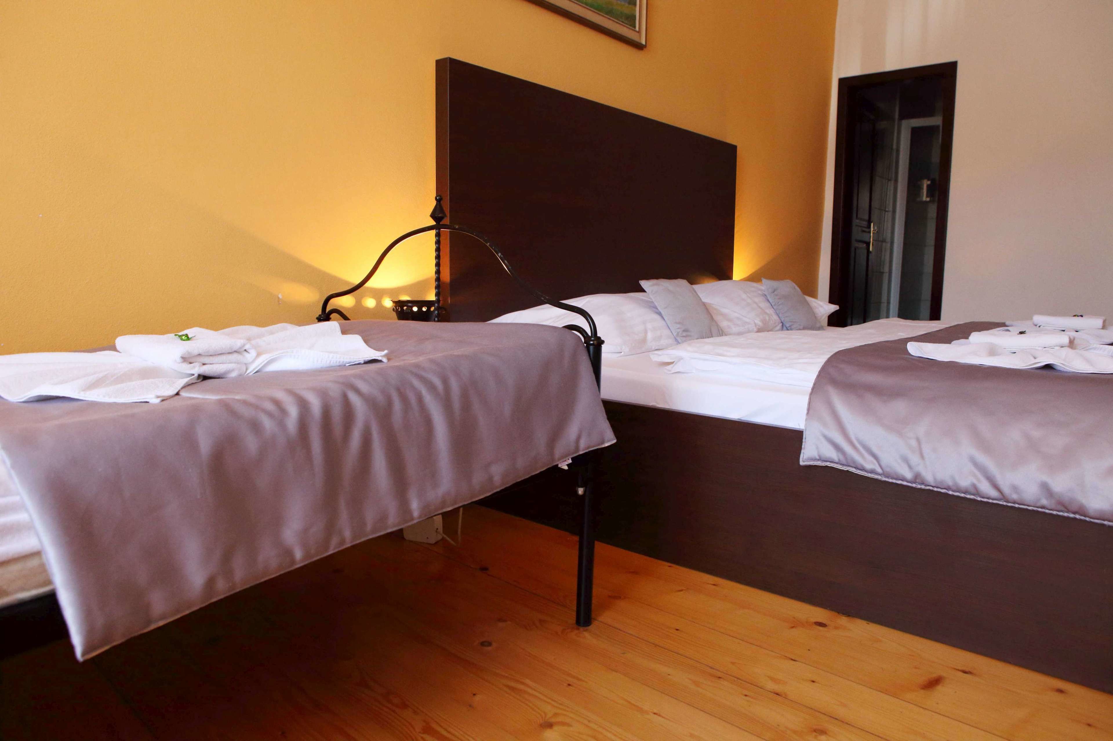 Une chambre d’hôtel avec deux lits, un plancher en bois et une table de chevet avec une lampe.