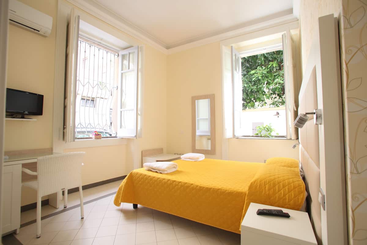 A bedroom with a bed, a desk, a chair, and a TV.