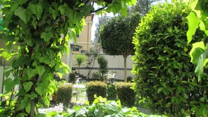 Een tuin met een fontein, omringd door verschillende planten en bomen.