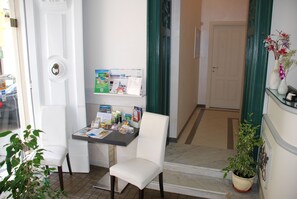 A small, clean room with a desk, two chairs, a potted plant, and a door. - Villa Vittoria (Tropea)