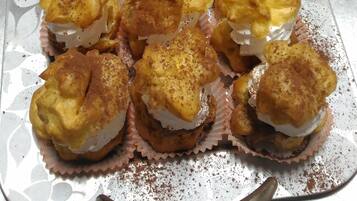 A tray of assorted pastries, including some with fruit toppings and others dusted with a spice, arranged on a metal tray.