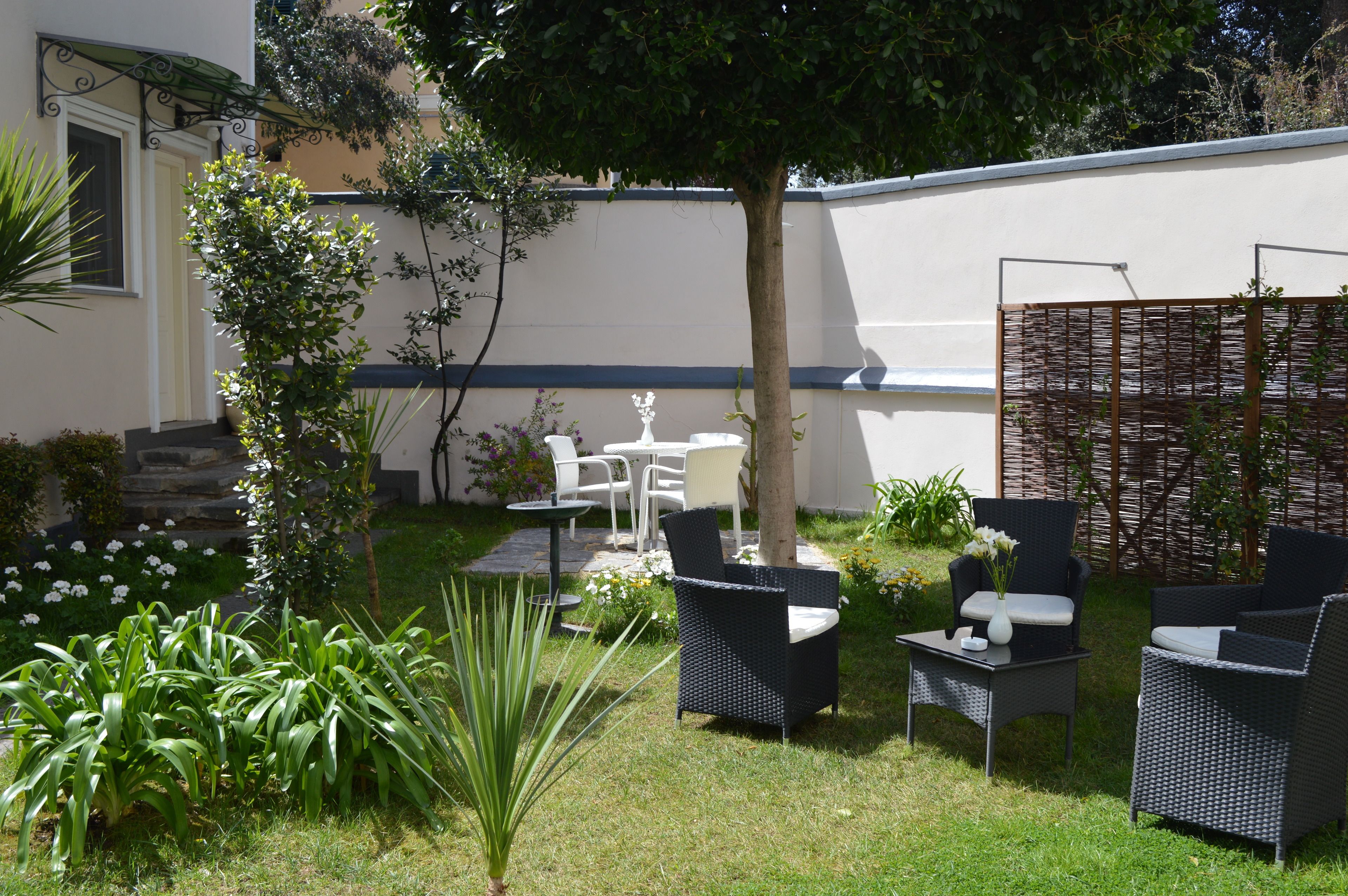 A patio with wicker furniture, a small table, and a decorative tree.