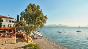 A seaside terrace with outdoor seating, a stone wall, and a view of the sea. - Leda Village Resort (South Pelion)