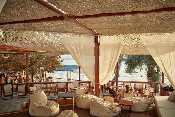 An outdoor seating area with wooden furniture and a view of the sea. - Leda Village Resort (South Pelion)