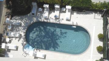 Una piscina al aire libre, sillones reclinables de piscina