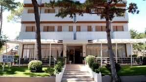 A multi-story hotel with a central entrance, surrounded by a covered outdoor area with seating.