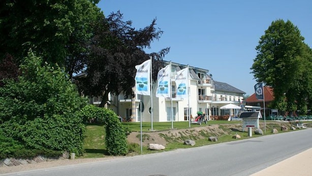 Un bâtiment moderne, orné de plusieurs drapeaux, avec un trottoir pavé et une route.