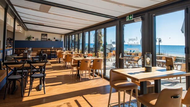 Un restaurante con amplios ventanales que ofrece vistas al mar.