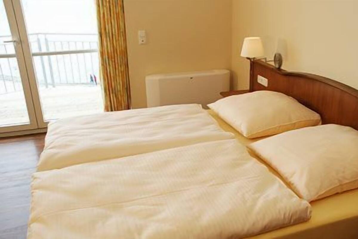 Un lit double avec deux oreillers, une tête de lit en bois et deux lampes de chevet.