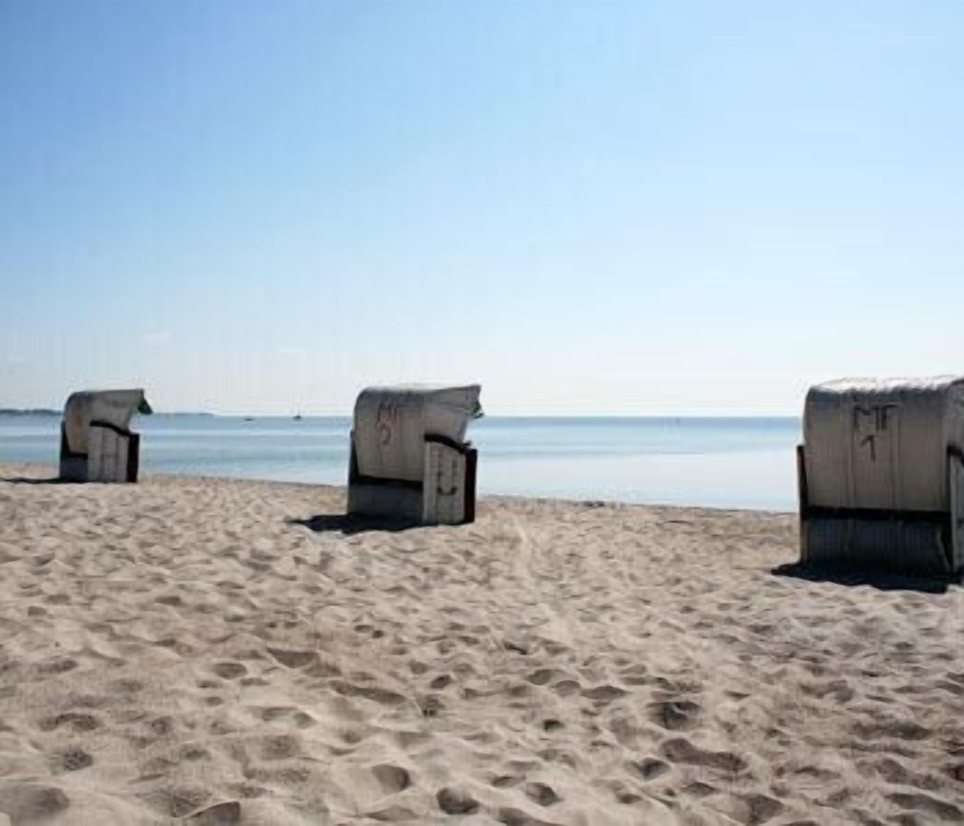 Una playa con tres estructuras de concreto, posiblemente zonas de descanso, a lo largo de la orilla.
