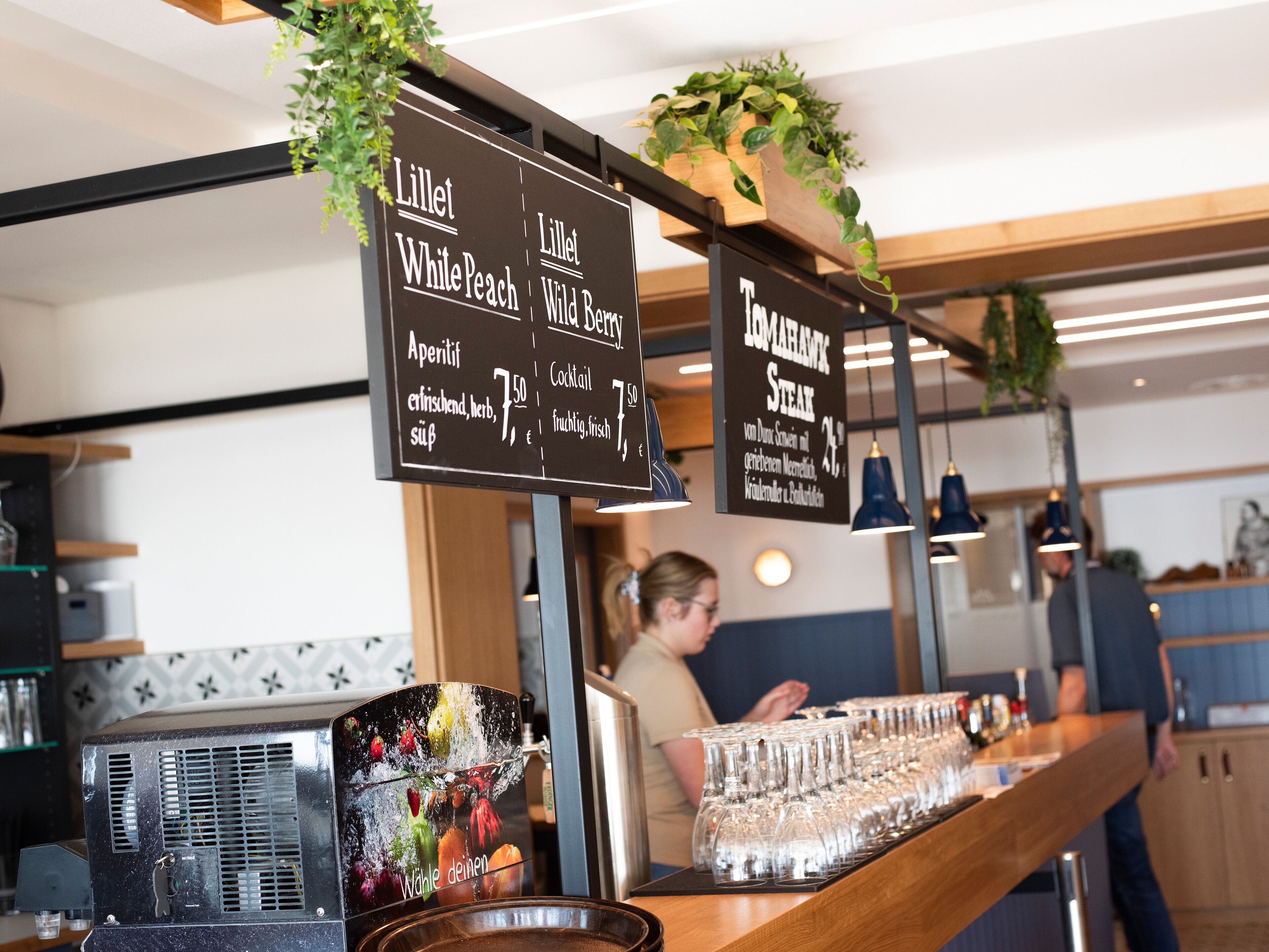 A bar area with a menu board listing drinks and a bar counter with glasses.