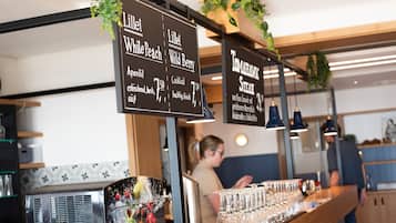 A bar area with a menu board listing drinks and a bar counter with glasses.