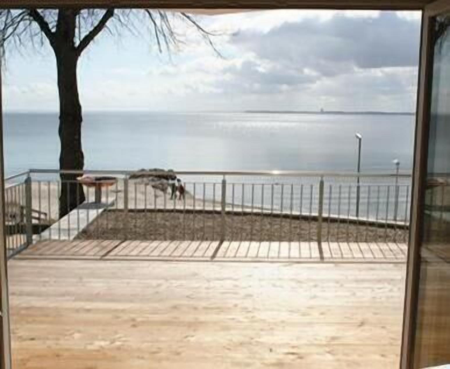 A wooden deck with a metal railing overlooking a body of water.
