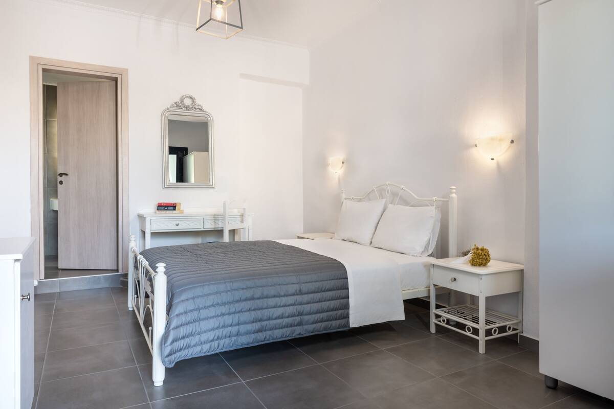 Un dormitorio moderno con cama, mesitas de noche, un espejo y un armario.